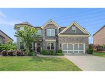 Beautiful two-story home featuring a well-manicured lawn and a gray brick and siding exterior at 3399 In Bloom Way, Auburn, GA 30011