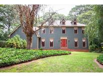 Charming two-story home with a well-maintained lawn, lush greenery, and a welcoming red front door at 2646 Kinnett Sw Dr, Lilburn, GA 30047