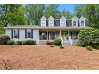 Charming home featuring a welcoming front porch, blue shutters, dormer windows, and a well-maintained front yard at 1767 Hunters Sw Trce, Lilburn, GA 30047
