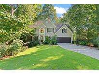 Charming home with lush green lawn, mature trees, and a welcoming two-car garage at 2185 Arbor Chase, Cumming, GA 30041