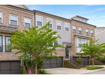 Beautiful multi-story brick townhome featuring an attached two-car garage and professionally landscaped front yard at 3592 Parkhaven Pl, Brookhaven, GA 30319