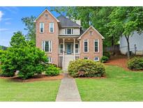 Charming two-story brick home featuring a well-manicured lawn and mature landscaping at 1145 Cool Springs Nw Dr, Kennesaw, GA 30144
