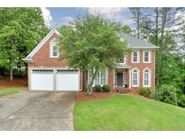 Charming two-story brick home featuring a well-manicured lawn, mature trees, and a two-car garage at 305 High Branch Way, Roswell, GA 30075