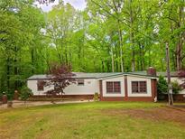 Cozy home exterior featuring well-maintained lawn and mature trees, offering a serene and private setting at 1720 Valley Ln, Cumming, GA 30040