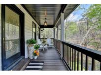 Inviting front porch with wooden deck, rocking chairs, and green plants at 443 Lakeshore Dr, Berkeley Lake, GA 30096