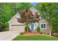 Charming exterior of home featuring a manicured lawn, blue front door, and lush landscaping at 1405 Arden Trace Ln, Lawrenceville, GA 30043