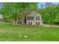 Charming two-story home with a lush green lawn, mature trees, and traditional architectural details at 3850 Pilgrim Mill Rd, Cumming, GA 30041