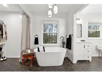 Bright bathroom with freestanding tub, modern fixtures, and a view of the trees at 650 Hunterhill Ct, Roswell, GA 30075