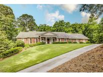 Classic brick home with a manicured front lawn and a long driveway on a wooded lot at 3845 Parian Nw Rdg, Atlanta, GA 30327