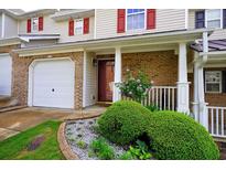 Charming townhouse featuring a brick facade, attached garage, and a beautifully landscaped front yard at 589 Fox Creek Xing, Woodstock, GA 30188