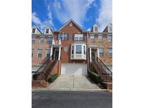 Brick townhome featuring an attached garage and well-maintained front yard landscaping at 6121 Joybrook Rd, Johns Creek, GA 30097