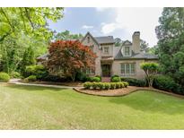 Charming brick home featuring a manicured lawn, mature trees, and classic architectural details at 1575 Spalding Dr, Sandy Springs, GA 30350
