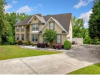 Traditional two-story home featuring a long driveway, a manicured lawn, and a neutral exterior paint at 209 Braemar Ct, Mcdonough, GA 30253