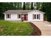 Charming one-story home with white siding, a red door, and lovely landscaping at 1563 Brannon Sw Cir, Austell, GA 30106