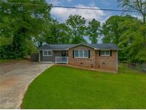 Charming single-story home featuring a brick facade, white trim, and a lush green lawn at 6892 Autumn Hills Dr, Douglasville, GA 30135