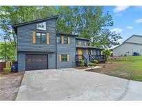Modern two-story home with a dark gray exterior, a black garage door and yellow door with lovely landscaping at 805 Wayside Dr, Lawrenceville, GA 30046