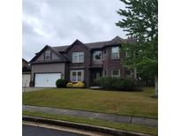 Inviting two-story home with a well-manicured lawn and a two-car garage, complemented by mature landscaping at 1474 Union Station, Lawrenceville, GA 30045