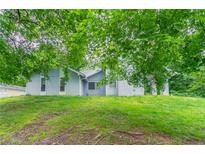 Charming home exterior with green lawn, partial view under trees at 6255 Saddlewood Dr, Lithonia, GA 30058