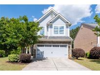 Charming two-story home featuring blue siding, stone accents, an attached garage, and a well-manicured front yard at 2341 Lily Valley Dr, Lawrenceville, GA 30045