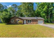 Charming single-story home features a brick facade, an attached garage, and a well-maintained lawn at 5326 Rocky Pine Dr, Lithonia, GA 30038