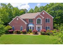 Charming two-story brick home featuring a well-manicured lawn and lush landscaping at 4734 Eagles Ridge Loop, Lithonia, GA 30038