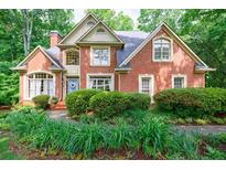 Charming brick home with a well-manicured lawn and mature landscaping at 745 Devon Hill Ct, Roswell, GA 30075