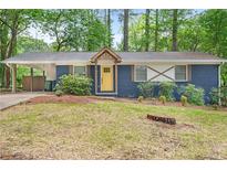 Charming blue brick home with a sunny yellow door, complemented by a well-maintained front yard at 3901 Bonnie Se Ln, Atlanta, GA 30354