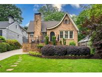 Charming brick home with a manicured lawn, garden bed, and front porch featuring black iron railings at 2580 Acorn Ne Ave, Atlanta, GA 30305