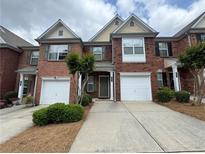 Traditional brick townhome featuring attached garage and manicured landscaping at 3871 Pleasant Oaks Dr, Lawrenceville, GA 30044