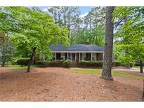 Charming brick home featuring a cozy front porch surrounded by lush, mature trees in a picturesque setting at 681 Hampton Sw Pl, Marietta, GA 30064