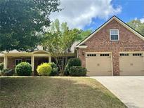 Charming brick home with a well-manicured lawn, attached two car garage and covered front porch at 3397 Holly Glen Dr, Dacula, GA 30019