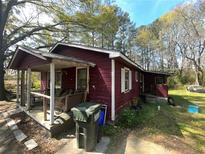 Exterior of a red single-story home with a covered front porch and overgrown yard at 6475 Church St, Atlanta, GA 30291