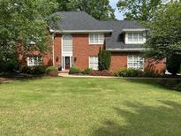 Charming two-story red brick home with well-manicured front yard and lush, mature trees at 999 Ashebrooke Ne Way, Marietta, GA 30068
