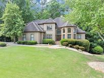 Stunning two-story home boasting a lush lawn, mature trees, and impeccable landscaping at 1455 Lockridge Dr, Cumming, GA 30041
