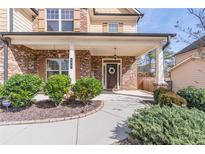 Inviting brick front porch with well-manicured landscaping, columns, and a charming front door at 965 Mulberry Bay Dr, Dacula, GA 30019