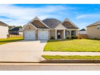 Charming brick home featuring a two-car garage, manicured lawn, and a welcoming facade under a clear blue sky at 1341 Midnight Ride Ct, Hampton, GA 30228
