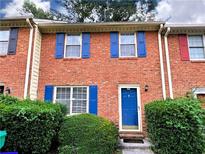 Charming brick townhome featuring a bright blue front door and lush green landscaping at 1038 Westfield Se Trce, Smyrna, GA 30082