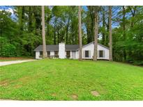 Charming single-story home with a well-maintained lawn and mature trees providing shade and curb appeal at 1490 Diplomat Dr, Riverdale, GA 30296