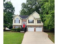 Inviting two-story home featuring a bright red front door, two-car garage, and well-maintained lawn at 136 Walkers Pond Dr, Villa Rica, GA 30180
