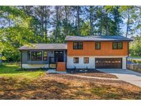 A charming two-story home featuring a two-car garage and gray and wood-paneled facade at 1129 Pinehurst Rd, Grayson, GA 30017