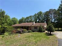 Charming single-story home with a well-maintained lawn, mature trees, and colorful flower beds at 7260 Cox Rd, Cumming, GA 30028