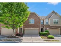 Charming brick townhome featuring a two-car garage and manicured landscaping under a sunny sky at 2167 Crestridge Ne Trl, Brookhaven, GA 30329