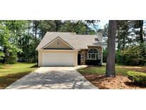 Charming single-Gathering home with stone accents, a two-car garage and a well-maintained lawn at 60 Whispering Pine Ct, Covington, GA 30016