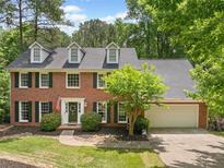 Charming brick two-story home with dormers, mature trees, dark shutters, and an attached two-car garage at 815 Lake Forest Pass, Roswell, GA 30076