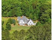 Aerial view of a charming white home with a well-manicured lawn surrounded by lush green trees at 300 Massengale Rd, Brooks, GA 30205
