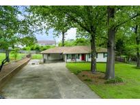 Charming single-story home with a well-maintained lawn, mature trees, and a welcoming red front door at 4147 Suzanne Ln, Duluth, GA 30096