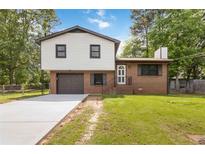 Charming two-story home with white siding, brick accents, a driveway, and an attached garage in a lush, green neighborhood at 2469 Silver King Dr, Grayson, GA 30017