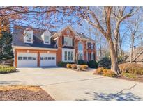 Elegant two-story brick home with a two-car garage and beautifully landscaped front yard on a sunny day at 1018 Jubilee Way, Powder Springs, GA 30127