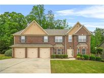 Charming brick two-story home boasts a three-car garage, manicured lawn, and lush landscaping at 4616 Town Manor Dr, Douglasville, GA 30135