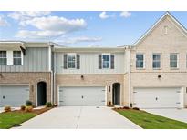 Charming townhomes with brick and gray siding, featuring attached garages and well-manicured lawns at 4667 Larkfield Way, Powder Springs, GA 30127